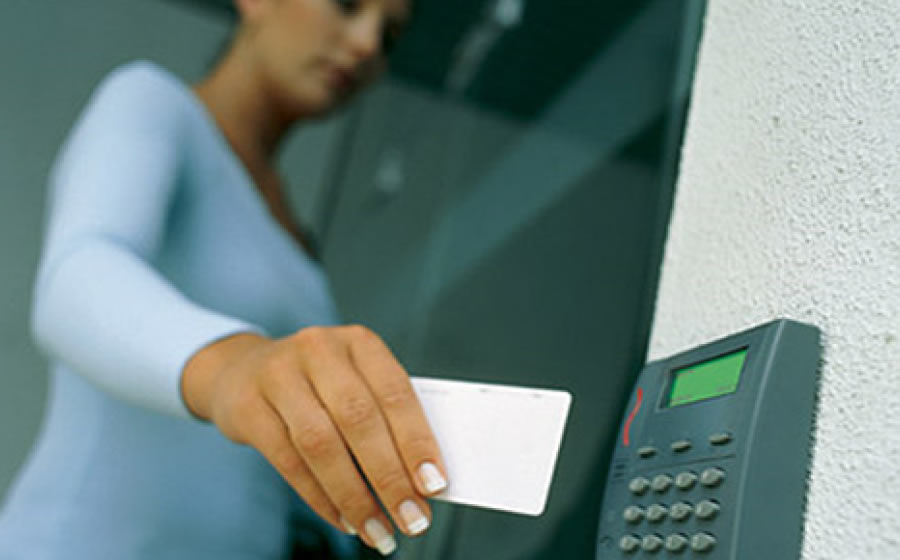 A woman scans a security access card at the entrance to a building.